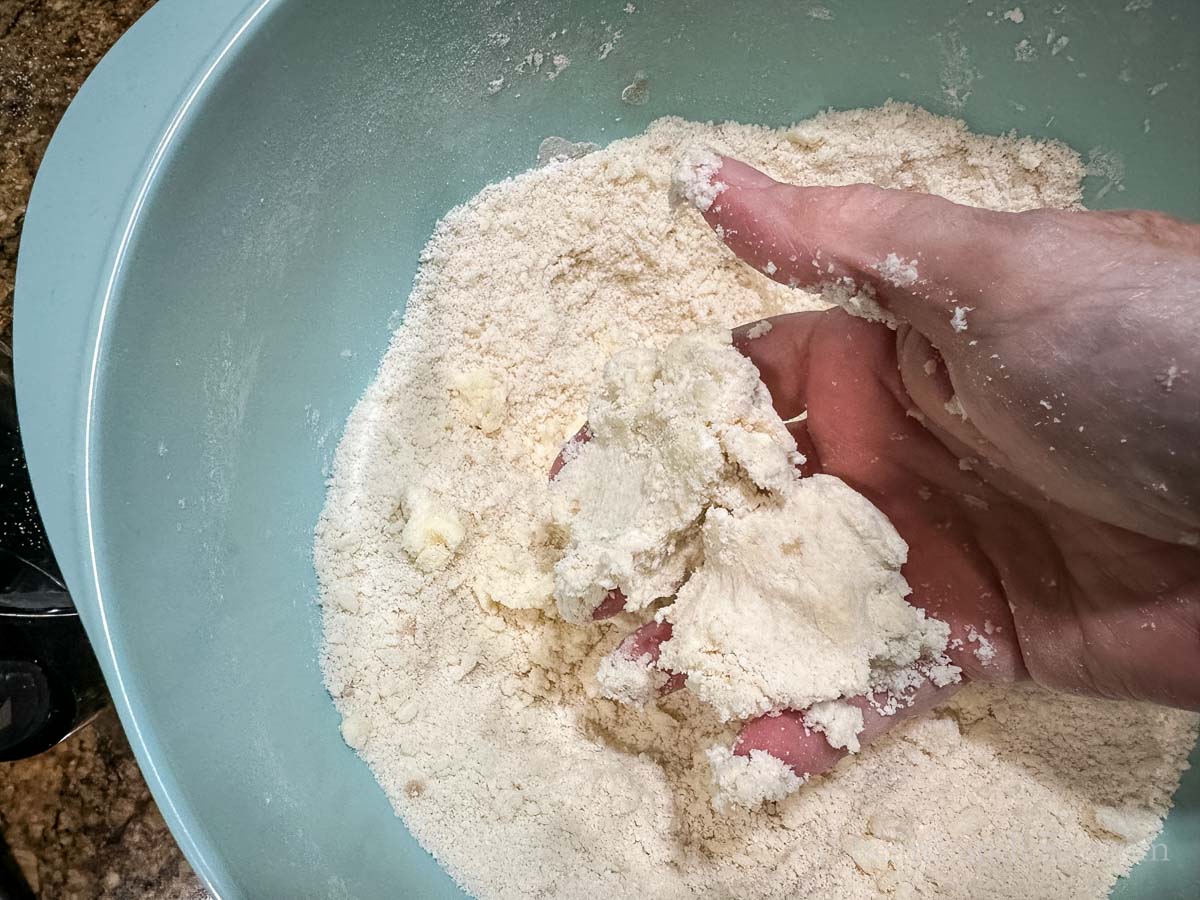 A hand squeezing together the dough mixture.