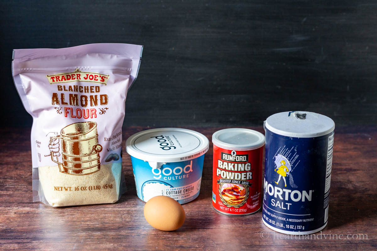 Ingredients for cottage cheese bagels including cottage cheese, an egg, almond flour, baking soda and salt.