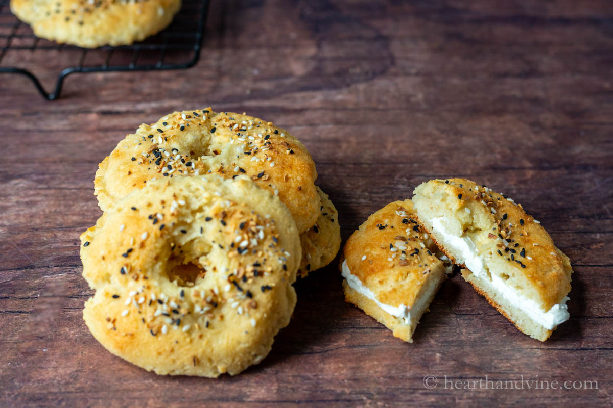Bagels stacked on the left and one cut in half and cream cheese spread inside.