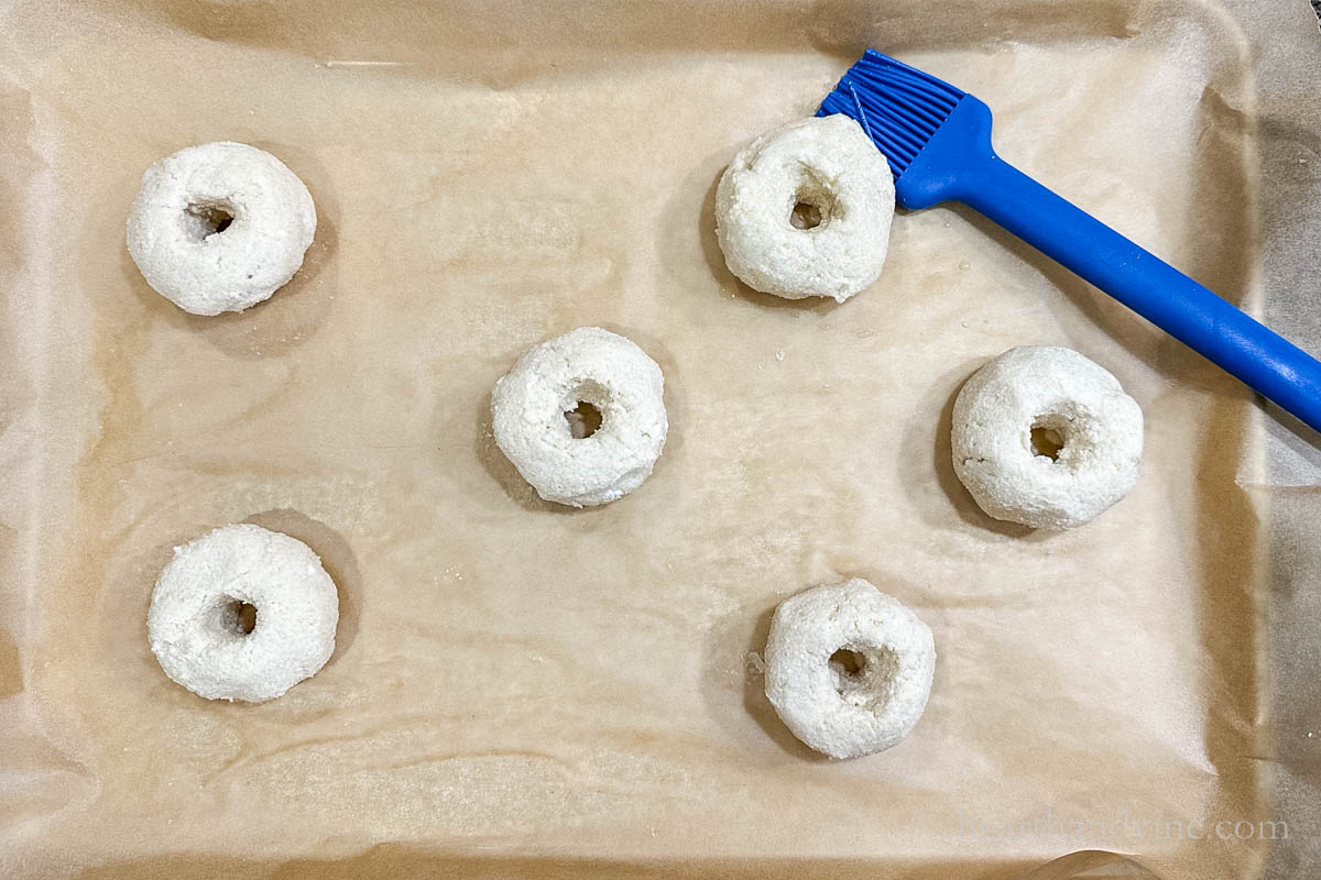 Balls of dough shaped into bagels and brushed with a egg wash.