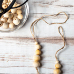 Wooden bead diffusers on twine with a pair of scissors and a bowl of beads on the side.
