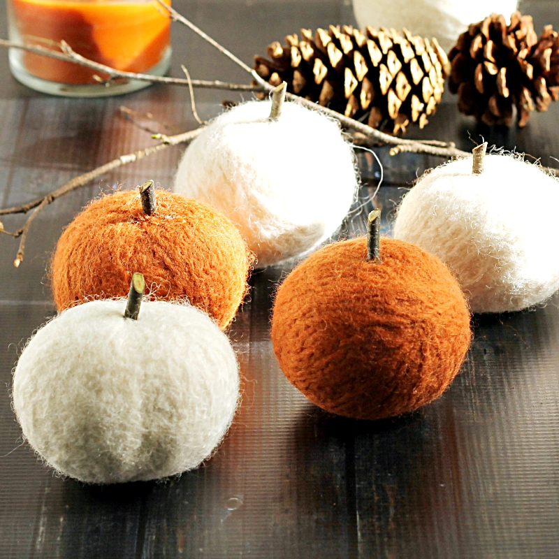 Yarn pumpkin craft with white and orange yarn.