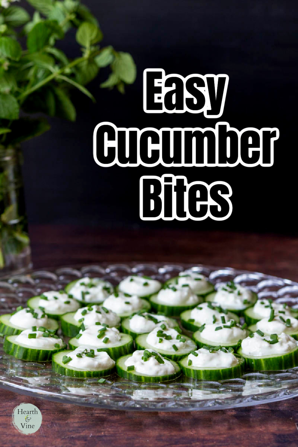 Cucumber bites with ranch dip and fresh chives set on a glass platter.