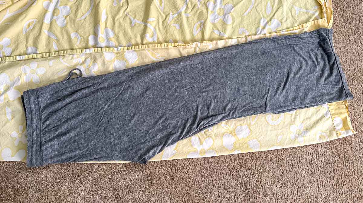 Laying old pants on folded sheet.