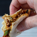 hand holding a slice of a chicken quesadilla.