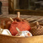 Handmade fabric pumpkins in a wooden bowl in different colored fabric.