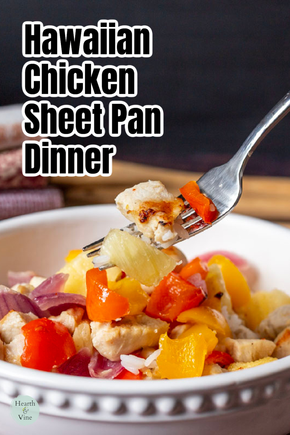 A fork lifting a bite of Hawaiian chicken dinner from a bowl.