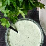 Bowl of green goddess dressing with a bunch of fresh flat-leaf parsley.