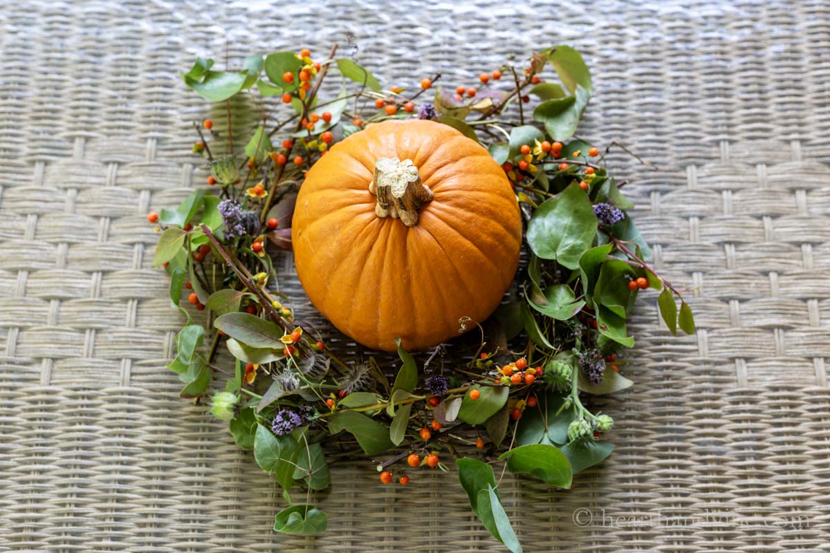 Foraged fall arrangement with a pumpkin in the center.
