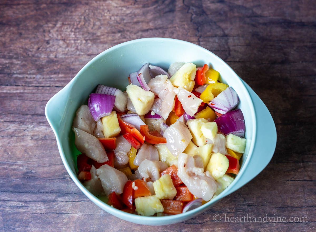 Chicken, veggies, pineapple and sauce mixed in a bowl.