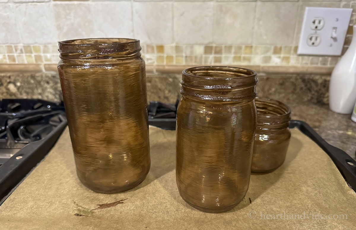 Painted clear glass jars to an amber tint on a baking sheet lined with parchment paper.