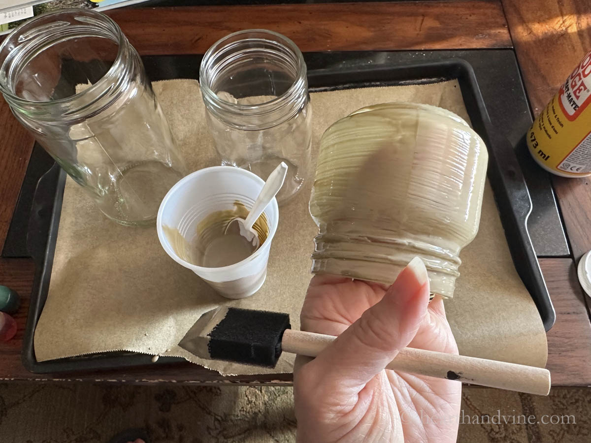 Painting clear glass jar with mod podge and food coloring.