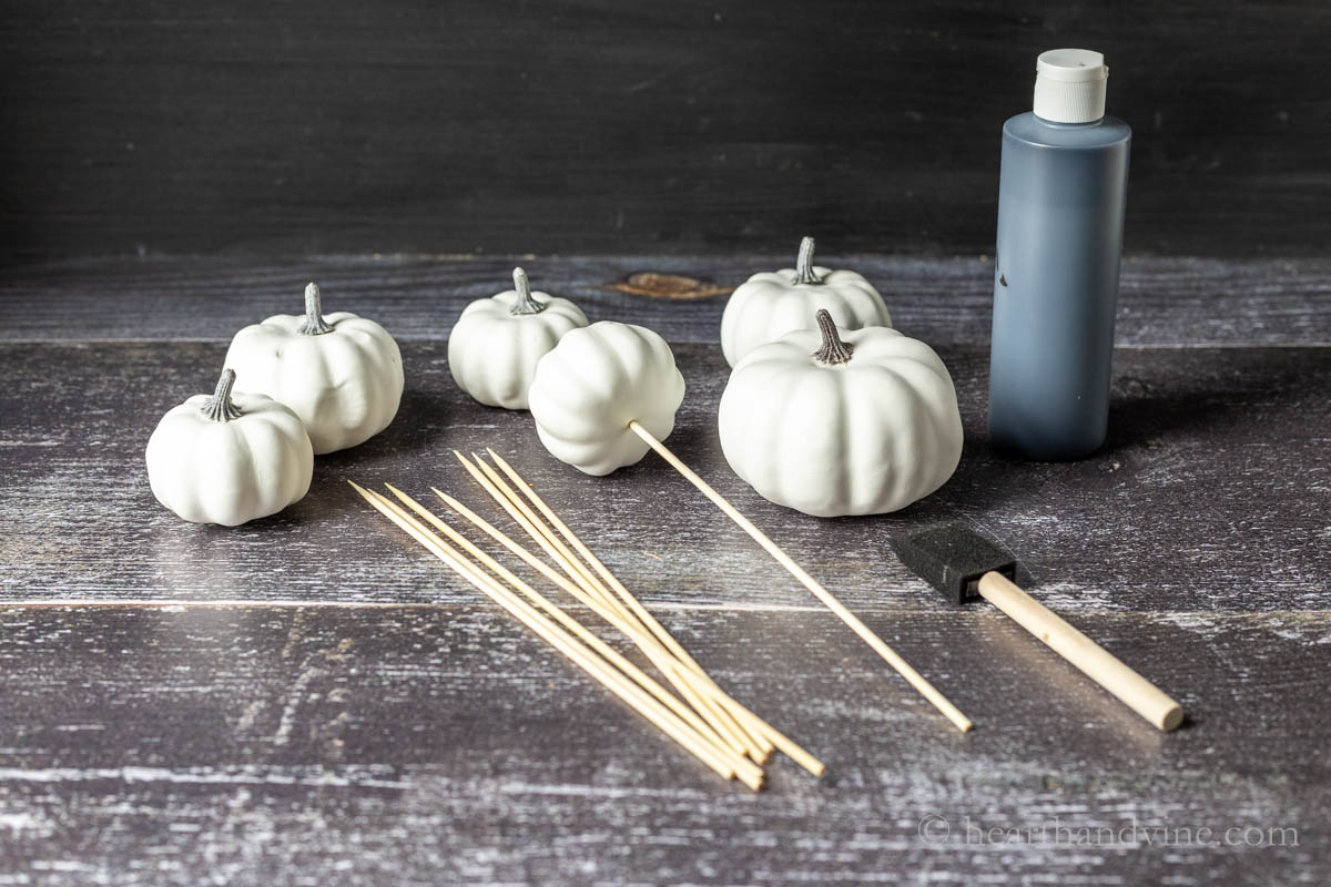 Faux mini white pumpkins, wooden skewers, a foam brush and black craft paint.