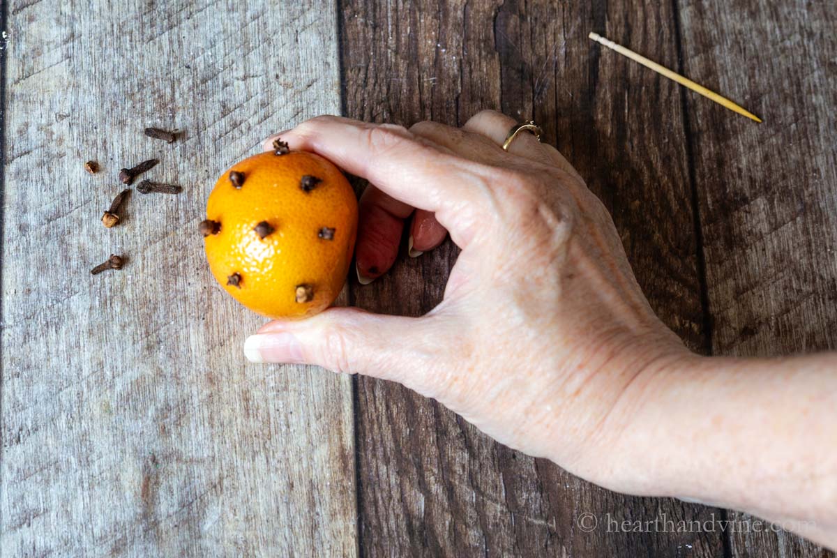 Making a mandarin orange pomander with whole cloves.