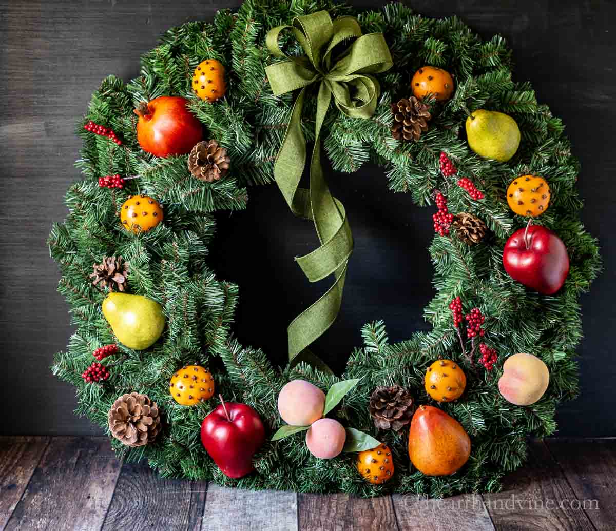 Williamsburg inspired fruit wreath aka Della Robbia on a table with a large green bow.
