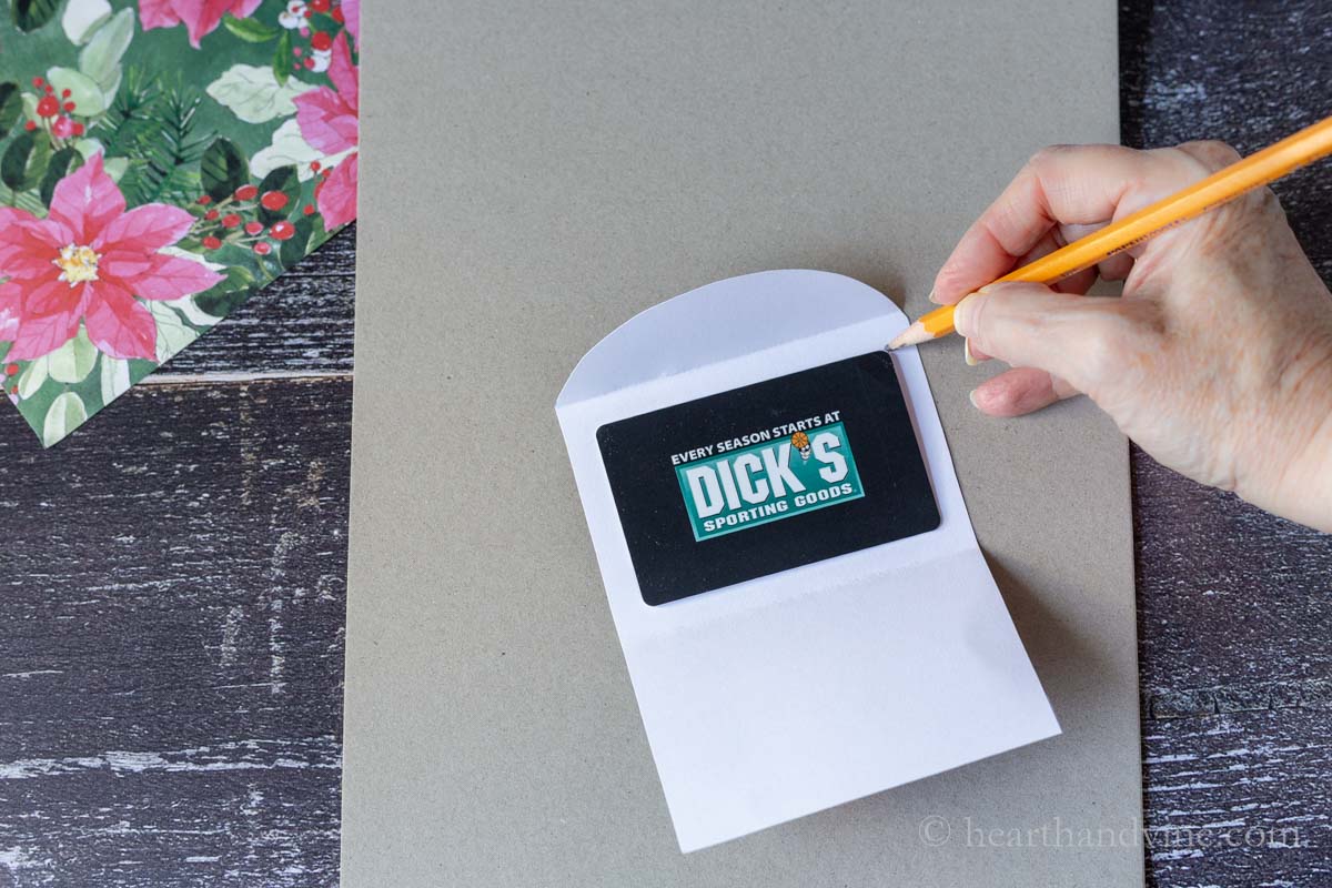 Making pencil markers on the upper right and lower left corners of a gift card on the upper portion of the holder.