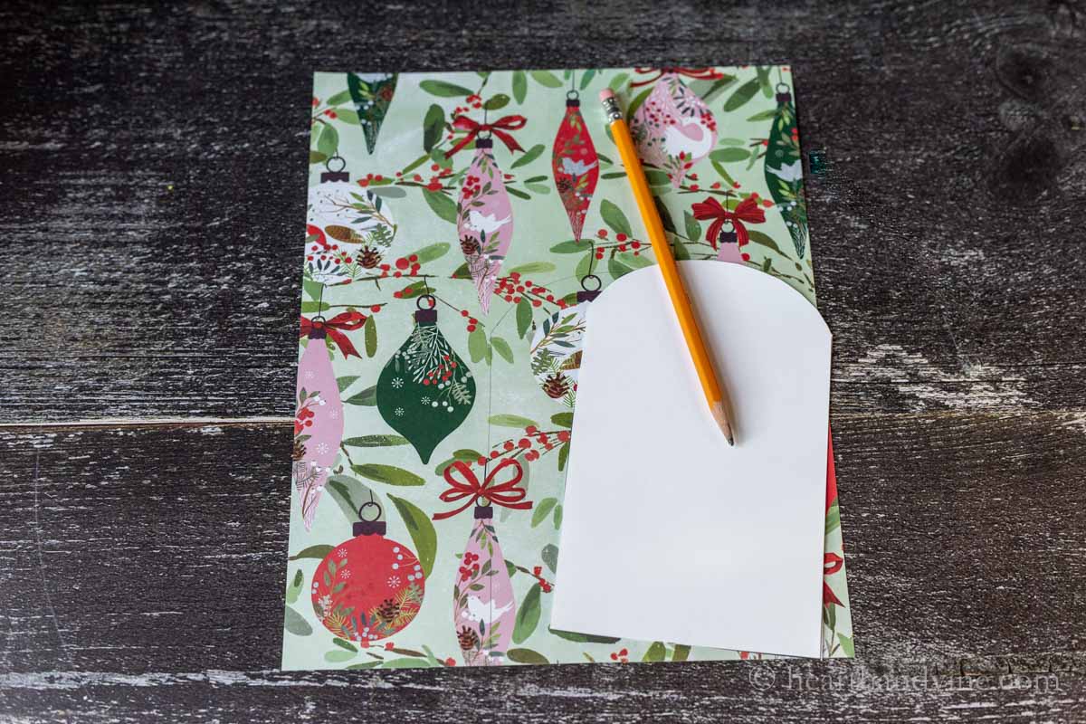 The blank gift card holder template traced onto a piece of holiday scrapbook paper.