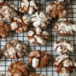 Chocolate crinkle cookies on a wire cooling rack.