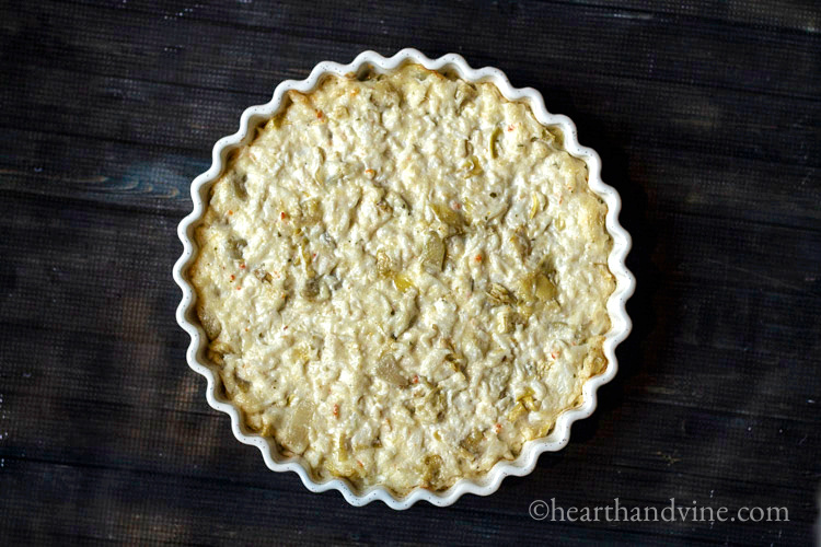 Artichoke dip with crabmeat baked in a deep dish pan.