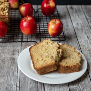 Slices of apple bread on a place with mini apples in the background.