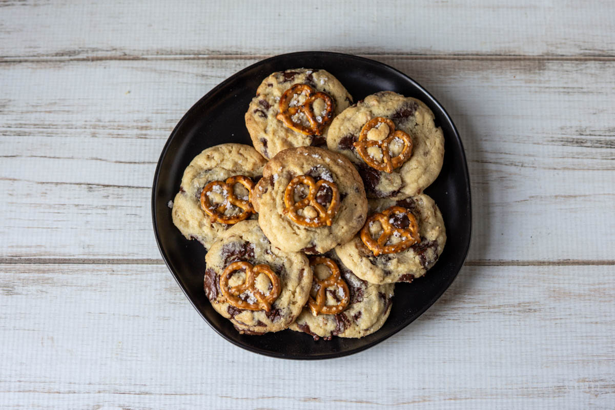 A plate of stacked chocolate chip caramel pretzel cookies.