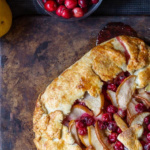 Partial view of a cranberry pear galette with a bowl of cranberries in the background.