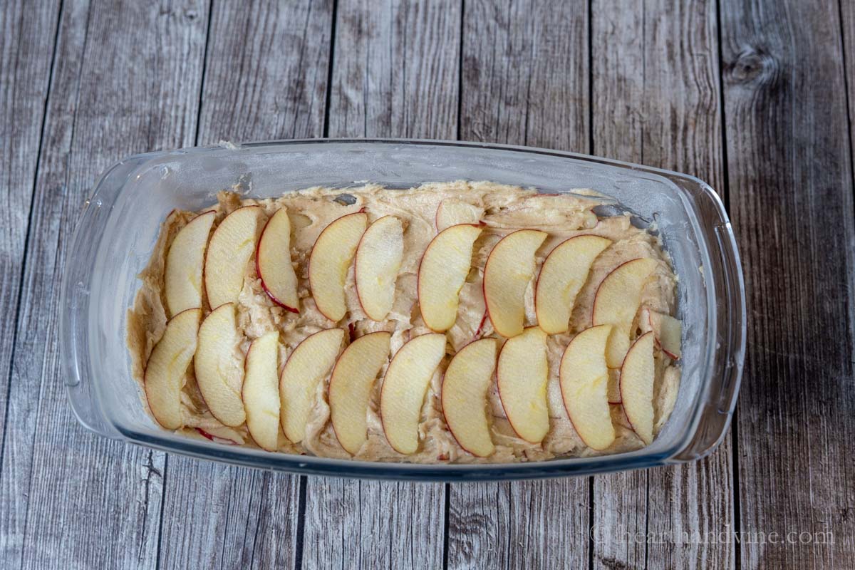 Thin slices of apple arranged on the top of the batter in a loaf pan.