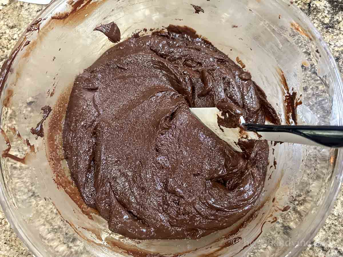 Chocolate fudge mixture in a large bowl with a rubber spatula.