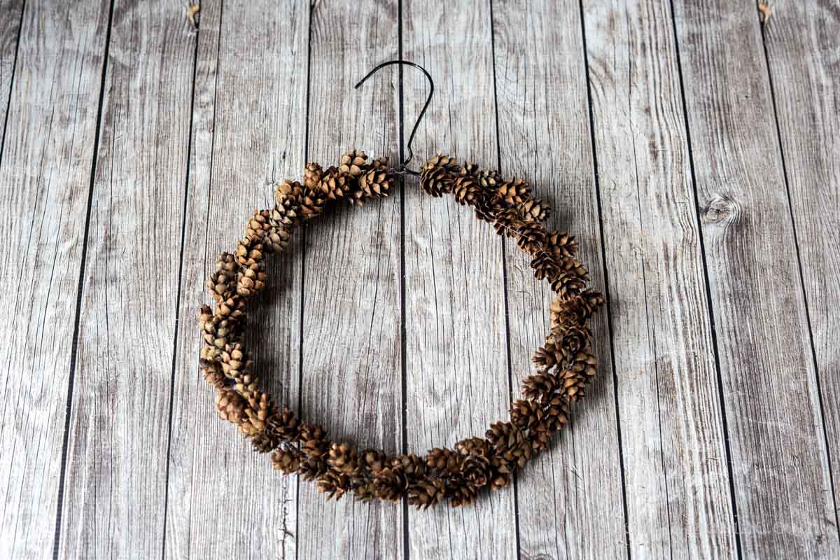 Mini pinecones glued to a wire coat hanger in a circular shape.