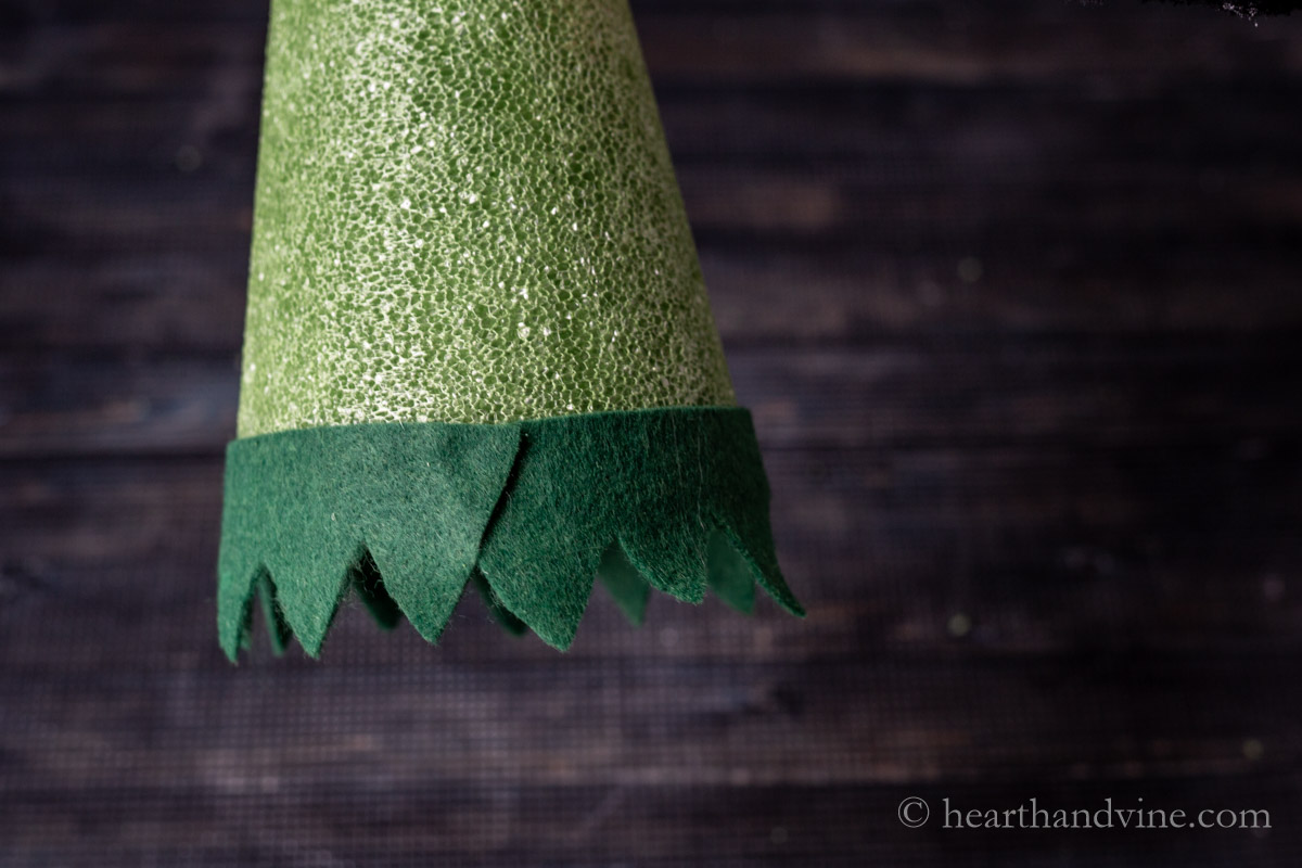 A band of leaf shaped cutouts glued to the bottom edge of a floral cone.