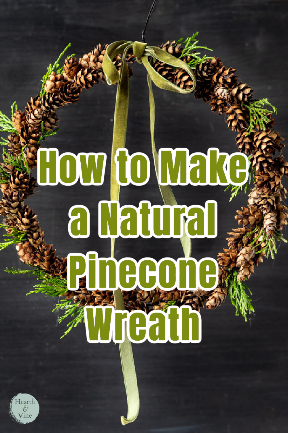 Mini pine cone wreath with green bow hanging from blackboard.