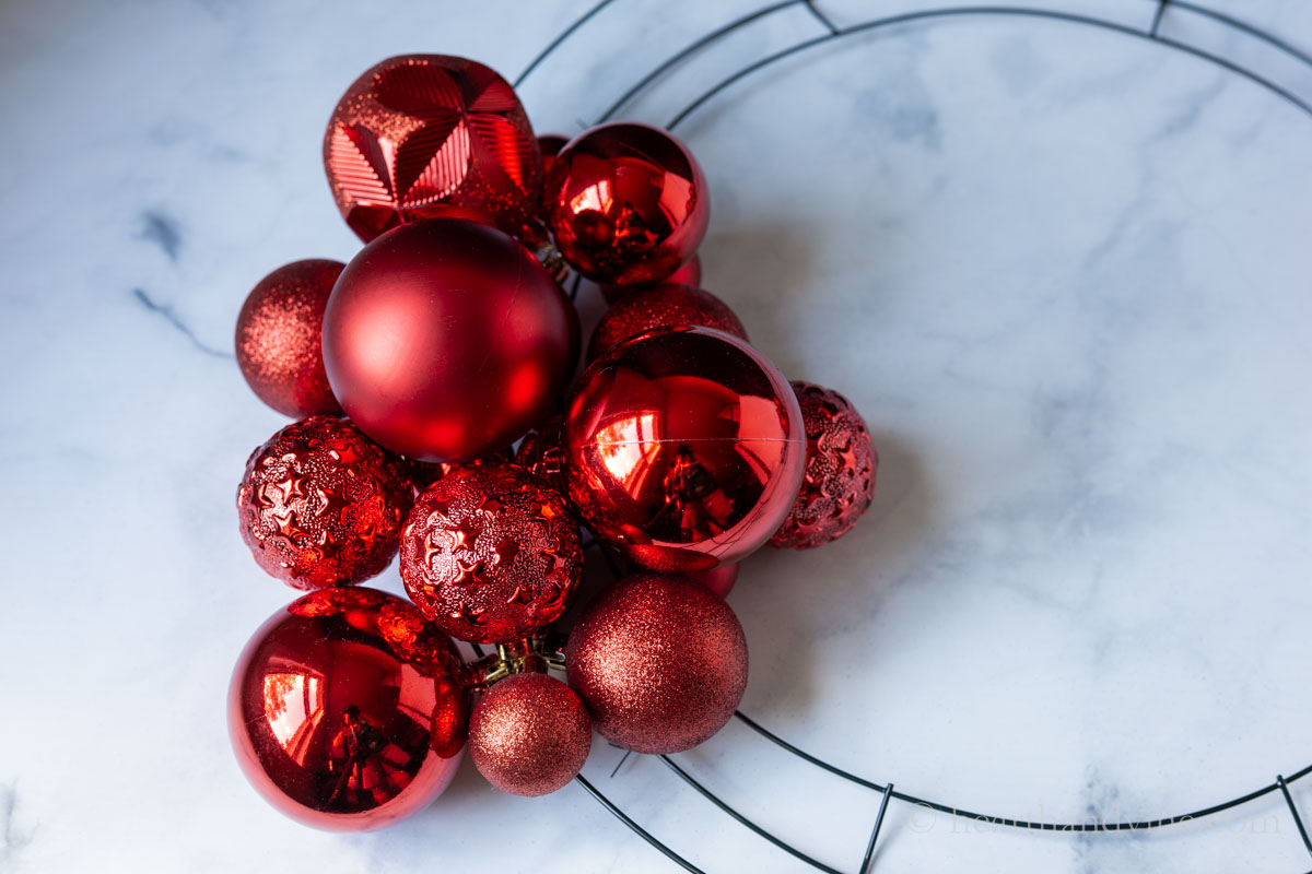 Clusters of red ornaments tied onto a wire wreath form.