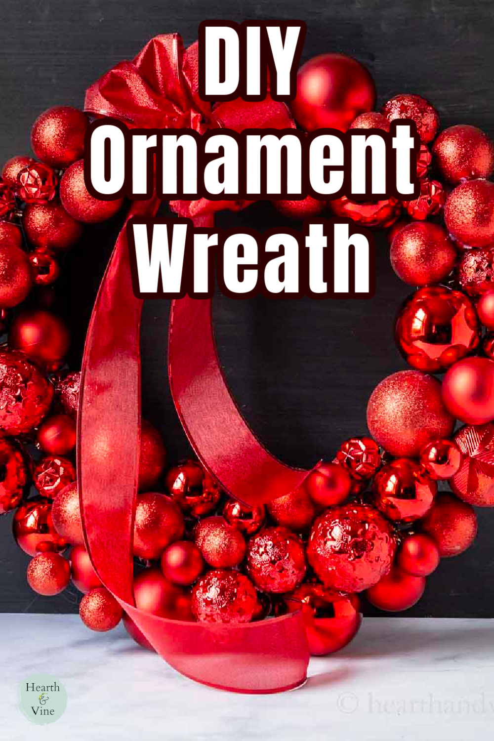 A red ornament wreath with a red bow leaning on a blackboard.