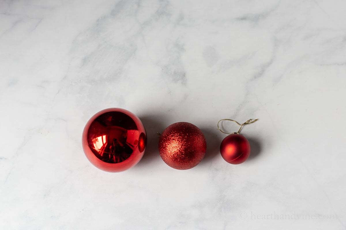 Three different sized red ornaments with different textures.