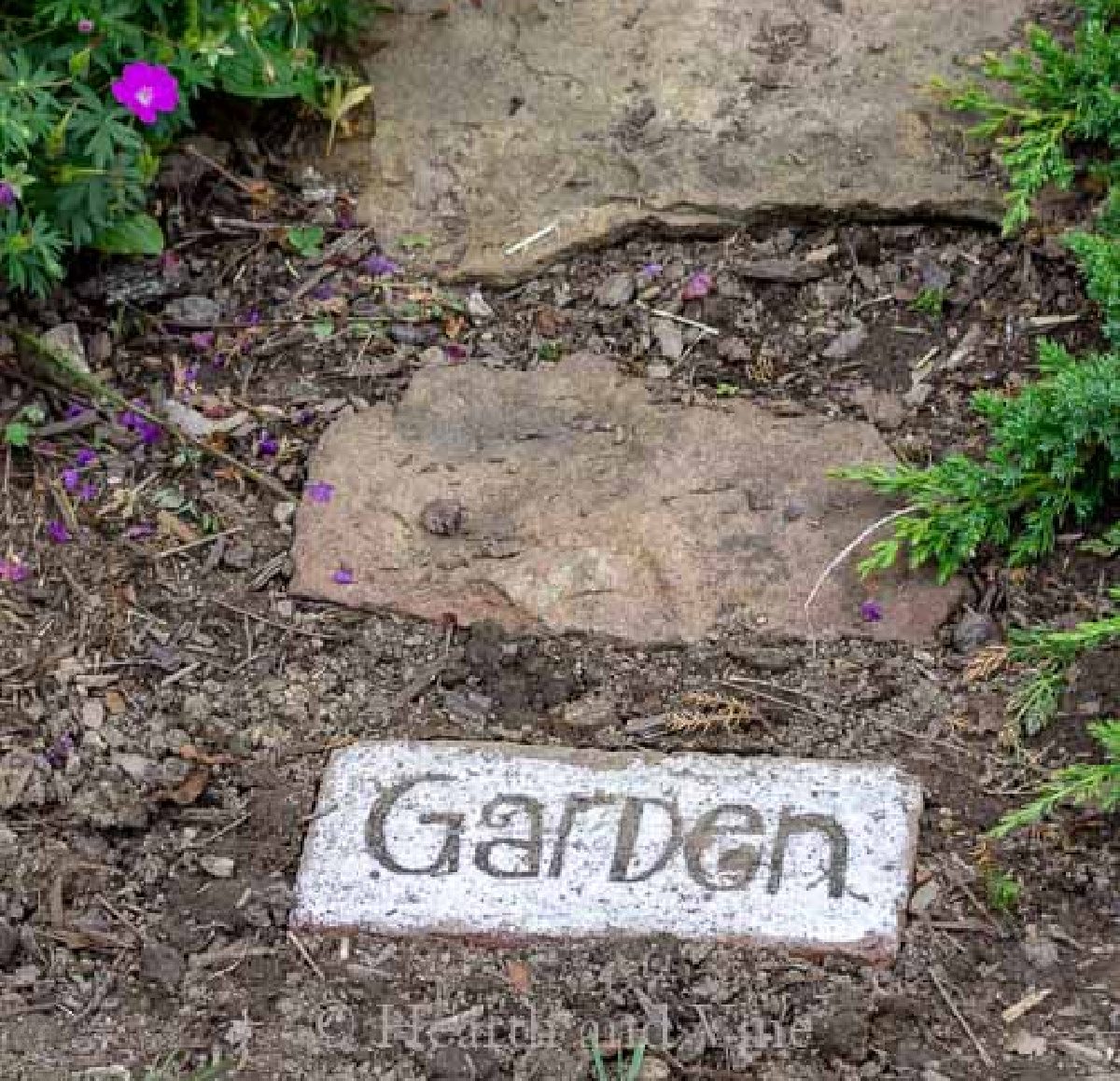 Painted brick as part of a path with the work "Garden."