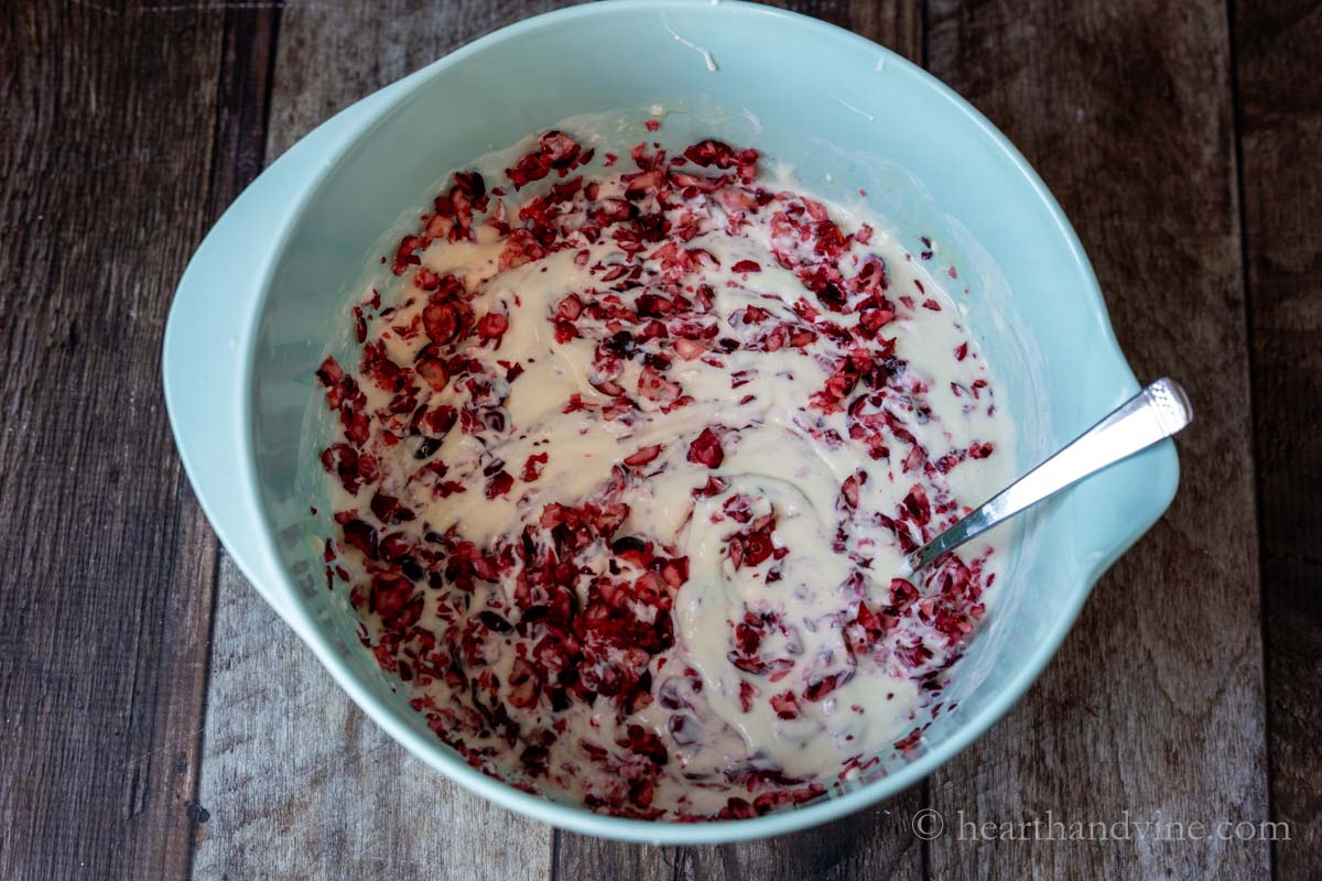 Folding fresh chopped cranberries into a mixture of cream cheese, sugar, vanilla, and lemon juice.