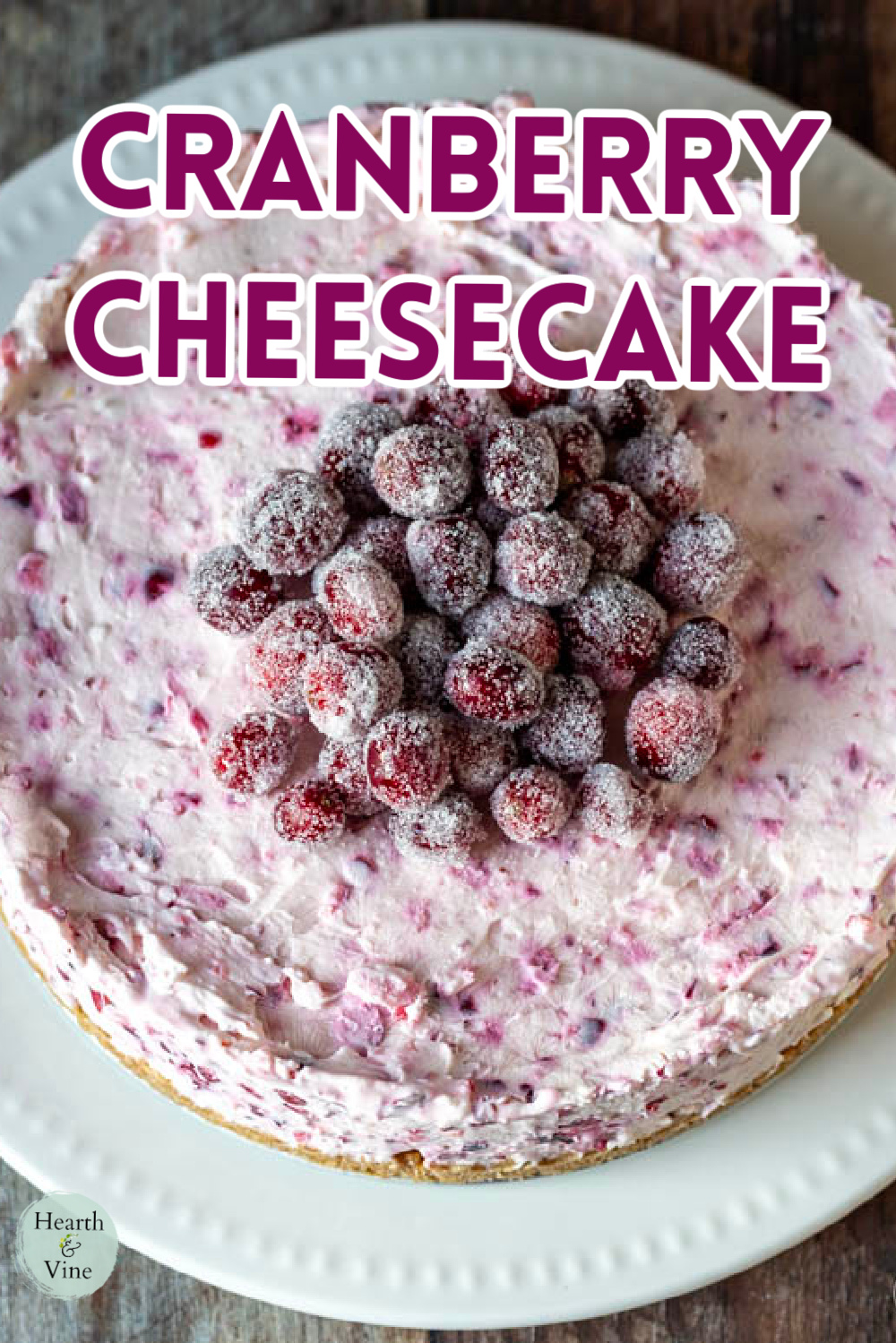 Cranberry cheesecake on a white plate adorned with sugared cranberries in the middle.