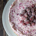 Aerial view of a partial cranberry cheesecake garnished with sugared cranberries.
