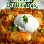 Chicken enchiladas on a plate with sour cream and cilantro leaves.