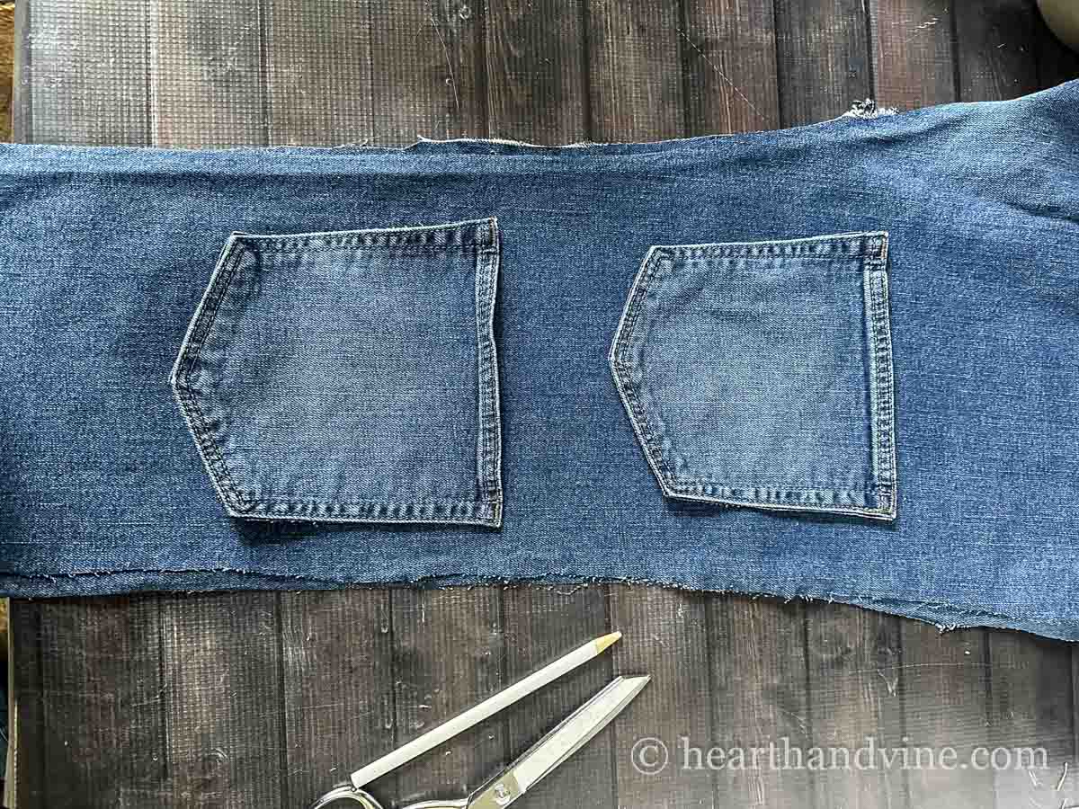 A long piece of denim with two denim pockets on top a few inches apart.