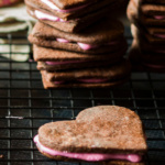 A sandwich cookie in a heart shape with pink frosting centers.