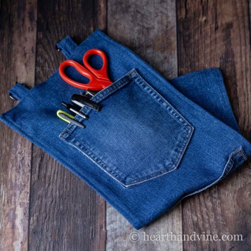 Jean pocket organizer folded on a table with scissors and pens in pocket.