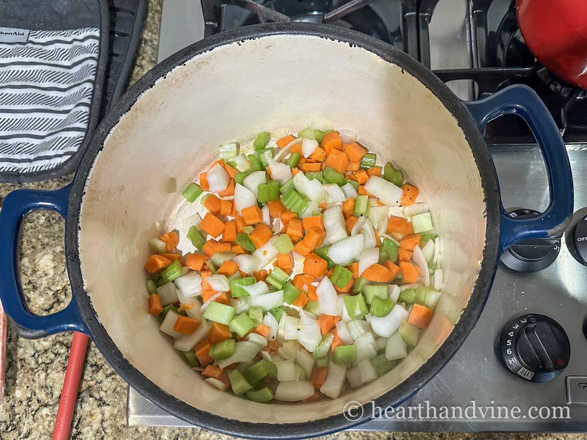 Freshly chopped onion, celery and carrots in a large soup pot on the stove.