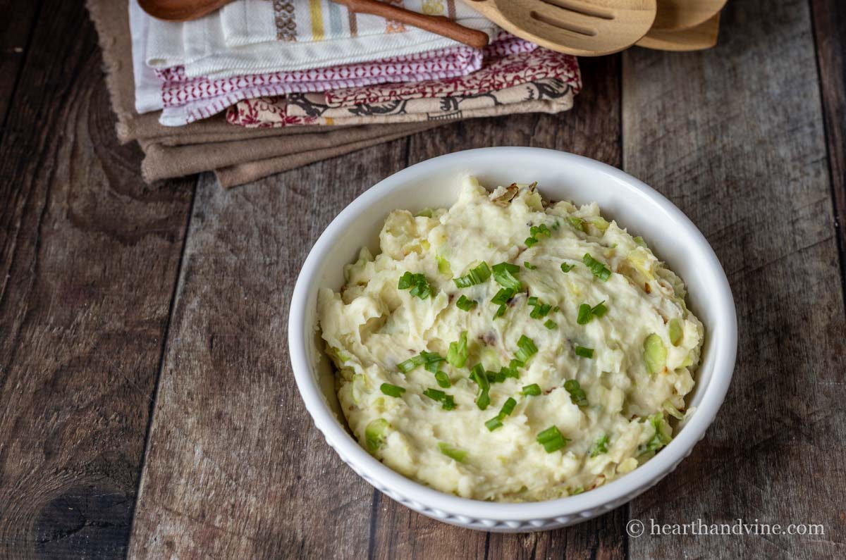 Bowl of Colcannon side dish with green onion garnish.
