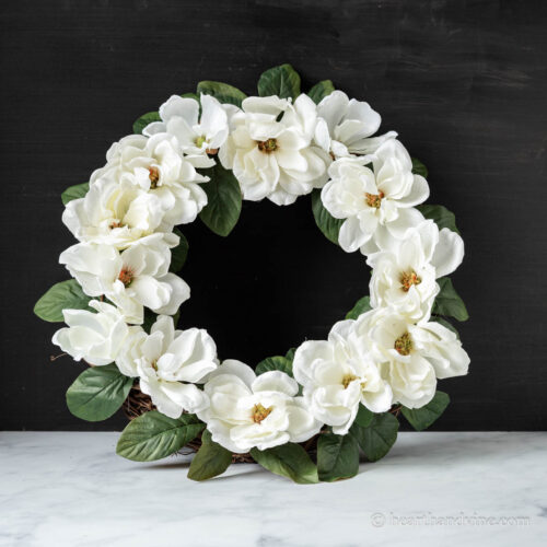 White magnolia flower wreath propped on a table.