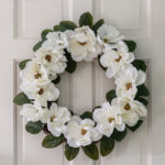 White flower magnolia wreath on a white door.