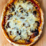Vertical look at a slow cooker pizza with mushrooms and cheese.