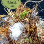 A close up look at a nesting materials ball for birds showing wool, moss, raffia, twigs and more.