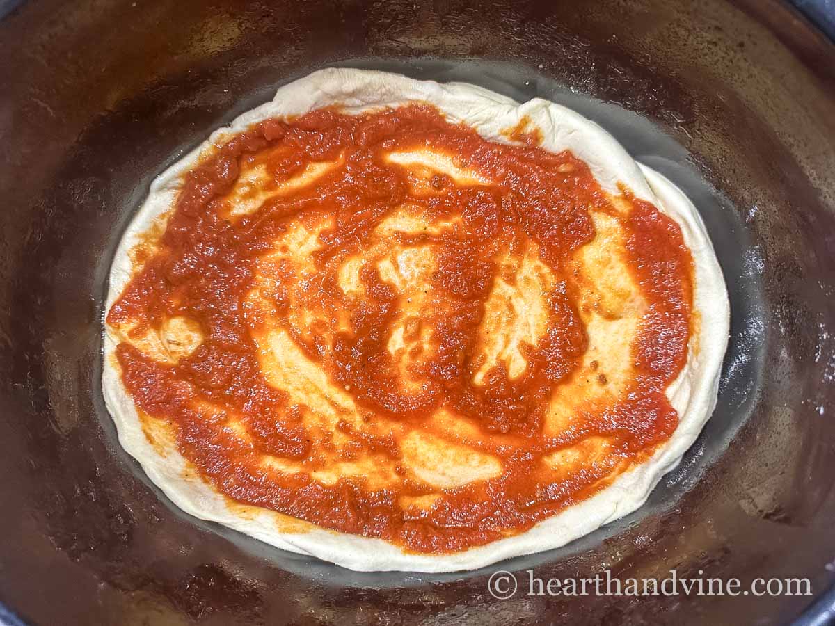 Pizza dough in the bottom of a slow cooker followed by marinara sauce.