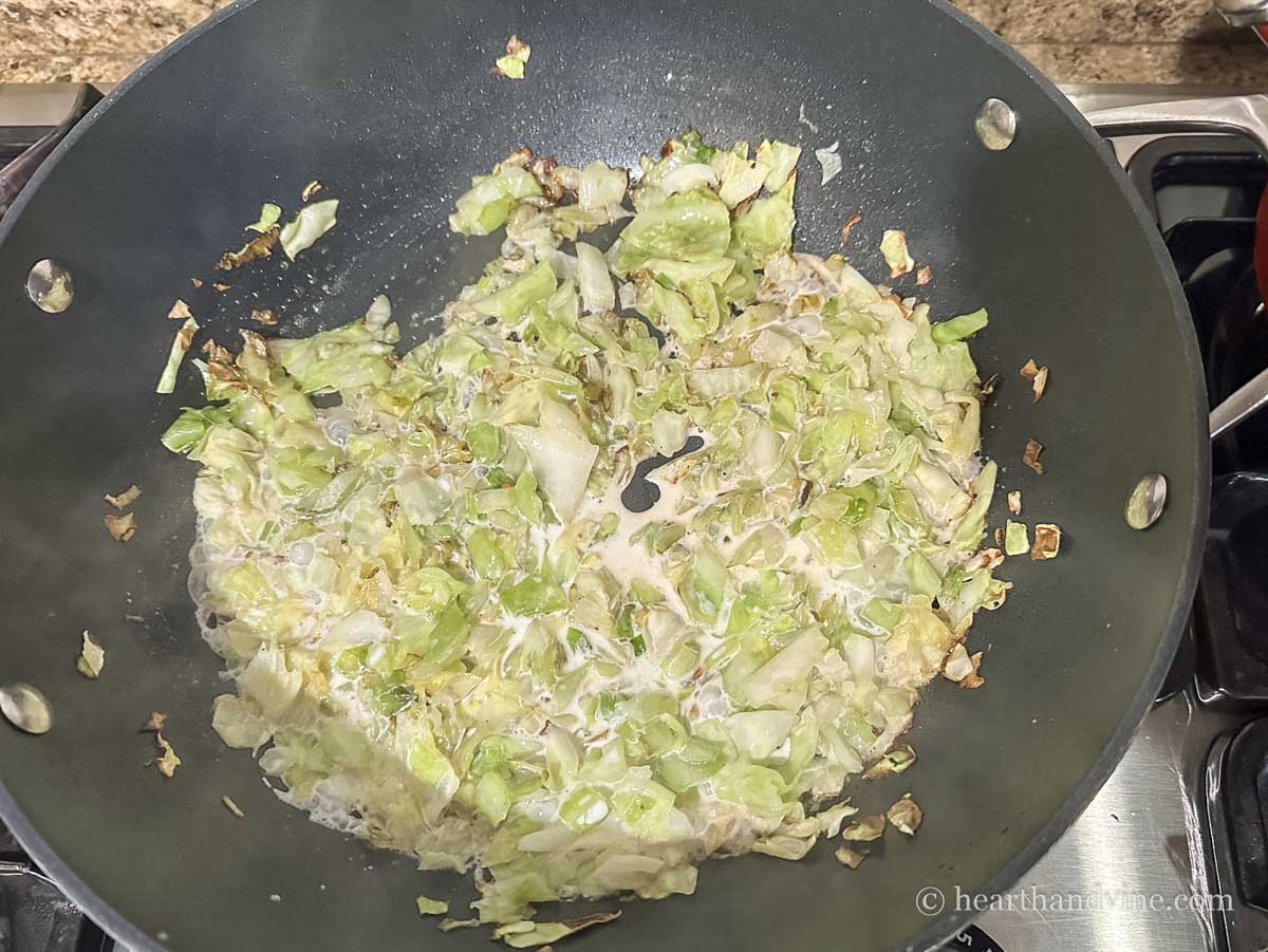 Sauteed cabbage and green onions with half & half in a skillet.